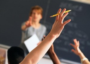 Teacher pointing to raised hands in classroom
