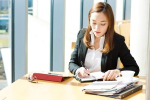 Businesswoman writing something on a note at Outdo