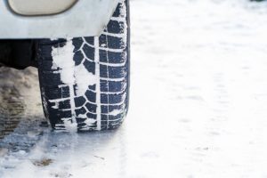 Car tires on winter road covered with snow. Vehicle on snowy alley in the morning at snowfall